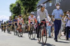 昨年7月、自転車で移動しながらヘルメットの着用を呼びかける近藤真彦さん（手前）＝高知市