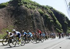 「ツール・ド・熊野」が開幕し、国の天然記念物「一枚岩」の前を走行する選手たち＝10日午前、和歌山県古座川町