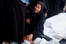 イスラエル軍による攻撃の犠牲者となった遺体のそばで泣く人＝6日、パレスチナ自治区ガザ南部ラファ（ロイター＝共同）