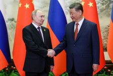 握手を交わすロシアのプーチン大統領（左）と中国の習近平国家主席＝16日、北京（タス＝共同）