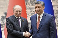 握手するロシアのプーチン大統領（左）と中国の習近平国家主席＝16日、北京（AP＝共同）