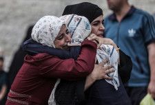 イスラエル軍の攻撃で犠牲者が出たパレスチナ自治区ガザ中部で抱き合う女性たち＝11日（ゲッティ＝共同）