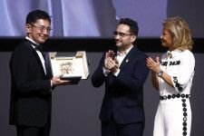 カンヌ国際映画祭でスタジオジブリが「名誉パルムドール」を受賞し、トロフィーを受け取った宮崎吾朗監督（左）＝20日、フランス・カンヌ（ロイター＝共同）