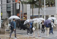 那覇市内を傘を差して歩く人たち。気象庁は沖縄地方と鹿児島県・奄美地方が梅雨入りしたとみられると発表した＝21日午前