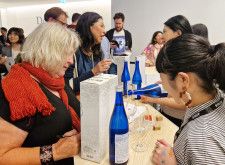 22日、ロンドンで開かれた能登半島地震復興支援イベントで石川県産の日本酒を試飲する来場者ら（共同）