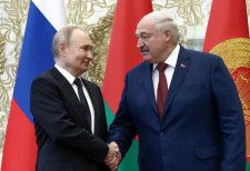 24日、ベラルーシ・ミンスクで会談し握手するルカシェンコ大統領（右）とロシアのプーチン大統領（ロイター＝共同）