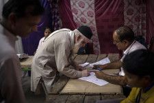 25日、インドの首都ニューデリーで下院総選挙の投票手続きをする男性（AP＝共同）