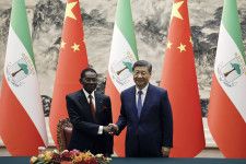 中国の習近平国家主席（右）と握手する赤道ギニアのヌゲマ大統領＝28日、北京の人民大会堂（AP＝共同）