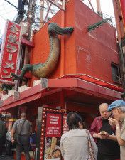 龍のしっぽ部分がはみ出ている「金龍ラーメン道頓堀店」の立体看板＝2023年10月、大阪市