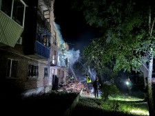 31日、ロシア軍のミサイル攻撃を受けた住宅と消防士ら＝ウクライナ東部ハリコフ（ロイター＝共同）