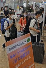 宮崎空港に到着した人たち。ゲート前には南海トラフ地震臨時情報に関する看板が設置されていた＝10日午前