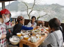 雄大な自然を眺めながら、手作りした豆腐や山菜の天ぷらを味わう参加者たち