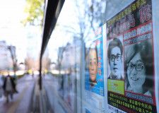 警視庁前に掲示された桐島聡容疑者（右手前）の指名手配のポスター（2024年1月、時事）