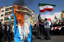 イランはシリアのイラン大使館攻撃を巡るイスラエルへの報復について、事態の急激なエスカレートを避け、性急な行動を取らない考えを仲介国を通じて米国に伝えた。イランの情報筋が明らかにした。写真は抗議活動でイスラエル国旗を燃やすイランの市民。４月５日、テヘランで撮影（２０２４年　Majid Asgaripour/WANA (West Asia News Agency) via REUTERS）