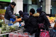 　４月１２日、英国立統計局（ＯＮＳ）が発表した２月の国内総生産（ＧＤＰ）は前月比０．１％増加でロイターがまとめたエコノミスト予想と一致した。写真は、英ロンドン南部クロイドンのサリー・ストリート・マーケットで、青果の屋台から生鮮食品を購入する客。２月撮影（２０２４年　ロイター/Hannah McKay）