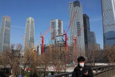 　４月１６日、中国国家統計局が発表した１─３月の不動産投資は前年同期比９．５％減と、１─２月の９．０％減から減少ペースが加速した。写真は建設現場の前を通り過ぎる男性。北京で２月撮影（２０２４　ロイター／Florence Lo）
