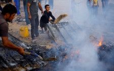 ５月２９日、国連安全保障理事会は、パレスチナ自治区ガザ情勢を協議する会合を開いた。米国はガザのパレスチナ人を保護するため一段の取り組みが必要だとし、支援物資搬入の障壁撤廃を訴えた。写真は２７日、イスラエルによる空爆の現場で火を消そうとする人たち。ラファで撮影（２０２４年　ロイター／Mohammed Salem）