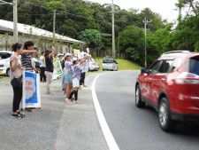 走行車両へ「ストップ！！ロードキル」の呼びかけを行う参加者ら＝6月25日、国頭村安田の県道70号沿い