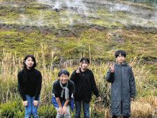 ２４年度に留学した中学生たちと里親の山田アリサさん（左から２人目）。後方は地熱によって水蒸気が噴出する穴（ひんぎゃ）が多数みられる斜面＝青ケ島村で