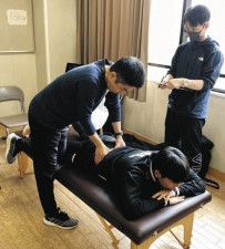 腰椎分離症の予防活動でサッカー部員の腰の状態を診る高松晃院長（左）＝名古屋市で（高松院長提供）