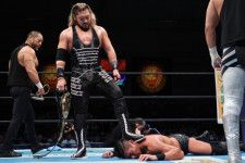 タッグマッチで勝利したEVIL（中央）はSANADAを踏みつけ、両手には強奪したベルトが握られていた。写真：新日本プロレスリング