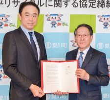 協定書を掲げる藤原常務（左）と小野澤町長（右）