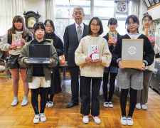 中田代表取締役（中央）と寄贈品を手に持つ代表児童ら