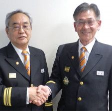 固い握手をする加藤新団長（右）と増田前団長＝栄消防署提供