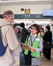 外国人観光客と話すボランティアの米山さん＝13日・鎌倉駅西口