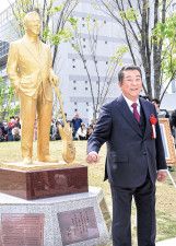 金色に輝くほぼ等身大の銅像とともに、笑顔を見せる加山さん＝茅ヶ崎市役所前広場