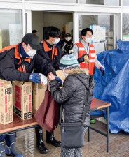 避難所で支援物資を手渡す市職員＝海老名市提供写真