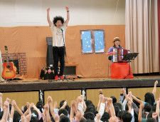 アコーディオンまいこさんの伴奏に合わせて、手を高く挙げ子どもたちと熱唱するタニケンさん