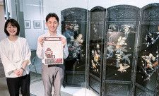 芝山師の宮崎さんが父と一緒に制作に携わった「芝山細工花鳥図屏風」の前で、ガイド代わりに配布している新聞を手に角田さん（右）と鈴木さん