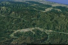 手前の谷あいが山形県小国町。右奥、新潟県村上市の日本海へ向けて「新潟山形南部連絡道路」の構想がある（画像：Google earth）。