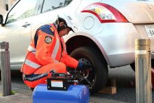 タイヤのトラブルで救援作業を行うJAF職員（画像：JAF）。