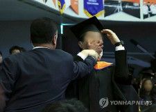 韓国科学技術院の学位授与式で警護員に口をふさがれる卒業生（大統領室通信写真記者団）＝１６日、ソウル（聯合ニュース）