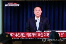尹大統領が国民向けの談話を発表する様子をソウル駅のテレビで見ている市民ら＝１日、ソウル（聯合ニュース）